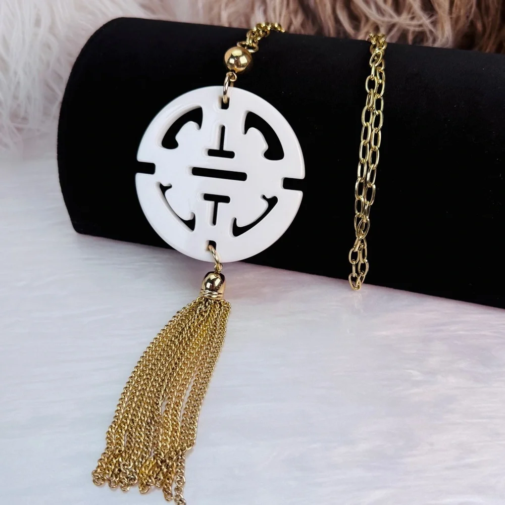 Long, goldtone, costume necklace, with large white pendant, and metal fringe